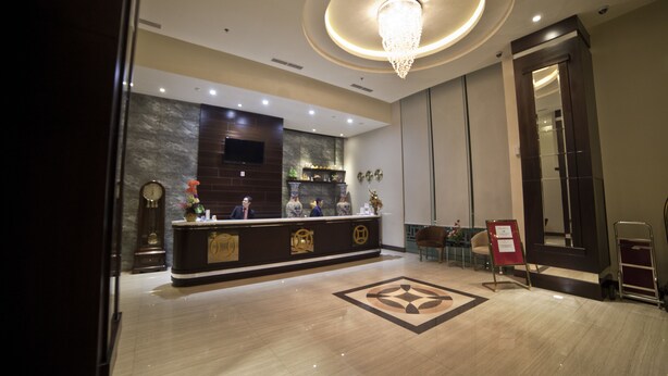 A hotel reception area with a marble floor, a reception desk, a chandelier, a clock, and a mirror. - Continent Centrepoint Hotel Makassar (Makassar)