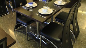 A restaurant with a dark wood table set for four, black chairs, and a modern interior design. - Continent Centrepoint Hotel Makassar (Makassar)