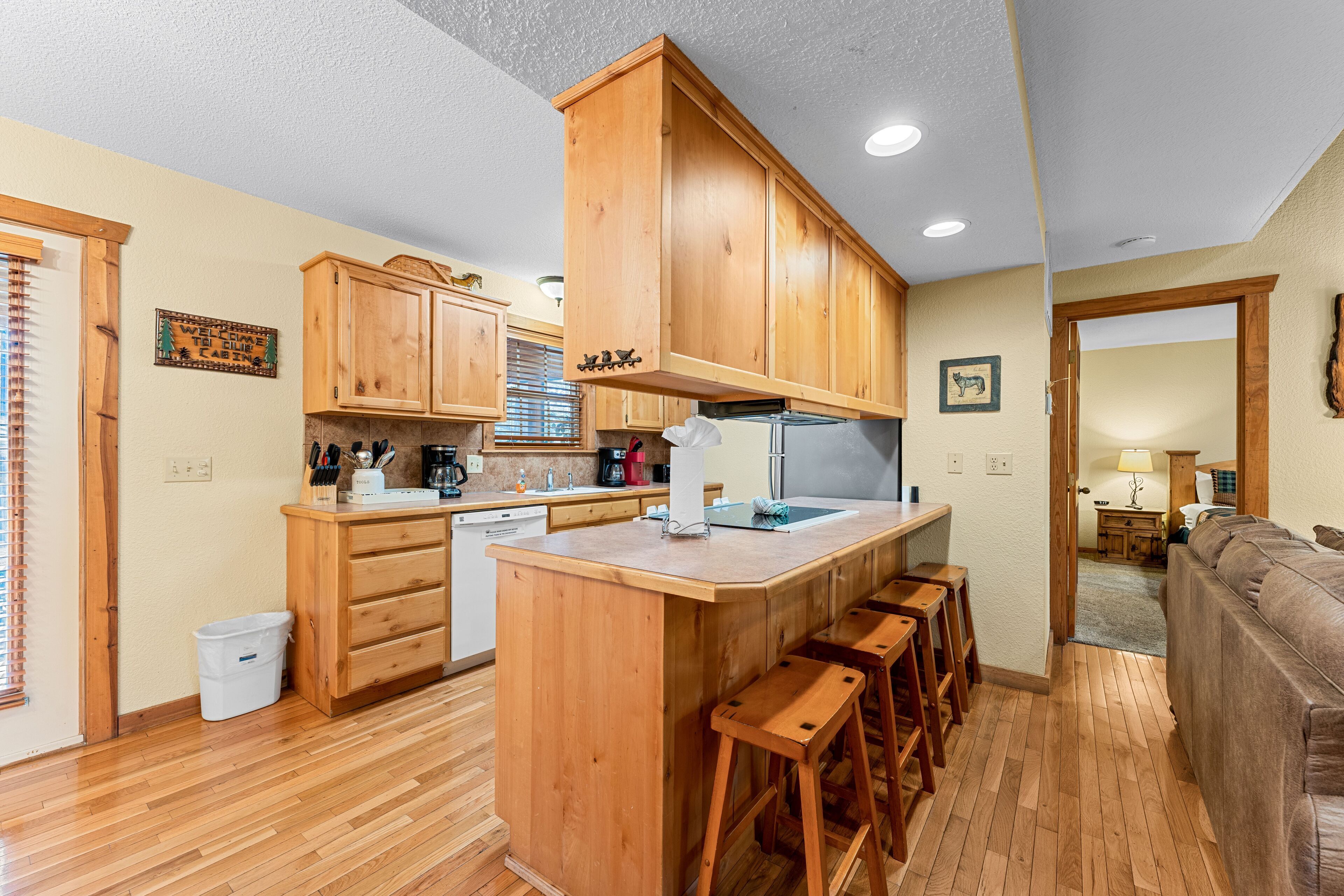 A kitchen with wooden cabinets, a central island with stools, a refrigerator, and a coffee maker.