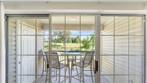 Ein Balkon mit Blick auf einen Golfplatz, einem Tisch und zwei Stühlen.