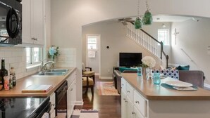 Une cuisine moderne dotée d’un îlot central, d’un coin repas avec un canapé et d’un escalier menant à une chambre à l’étage.