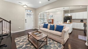 Un salon moderne avec un canapé beige, une table basse et un ventilateur de plafond.