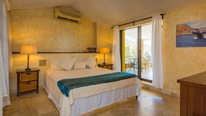 A bedroom with a large bed, two bedside tables with lamps, a view of the outdoors through a sliding door, and a wall-mounted air conditioner. - Luxury Private Villa-  Walk to Town, Pedregal, WiFi... (Cabo San Lucas)