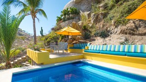 A swimming pool with a yellow and blue deck, a palm tree, and a rocky hillside in the background. - Luxury Private Villa-  Walk to Town, Pedregal, WiFi... (Cabo San Lucas)
