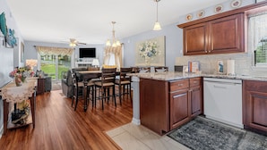 A modern kitchen with wooden cabinets, a granite countertop, and a built-in dishwasher. - Uniquely charming Pet Friendly 2 Bed condo near the strip at Pointe Royale! (Branson)