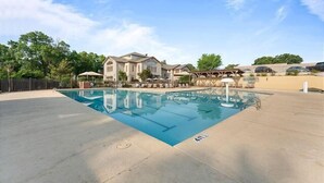 A swimming pool with a house in the background. - Uniquely charming Pet Friendly 2 Bed condo near the strip at Pointe Royale! (Branson)