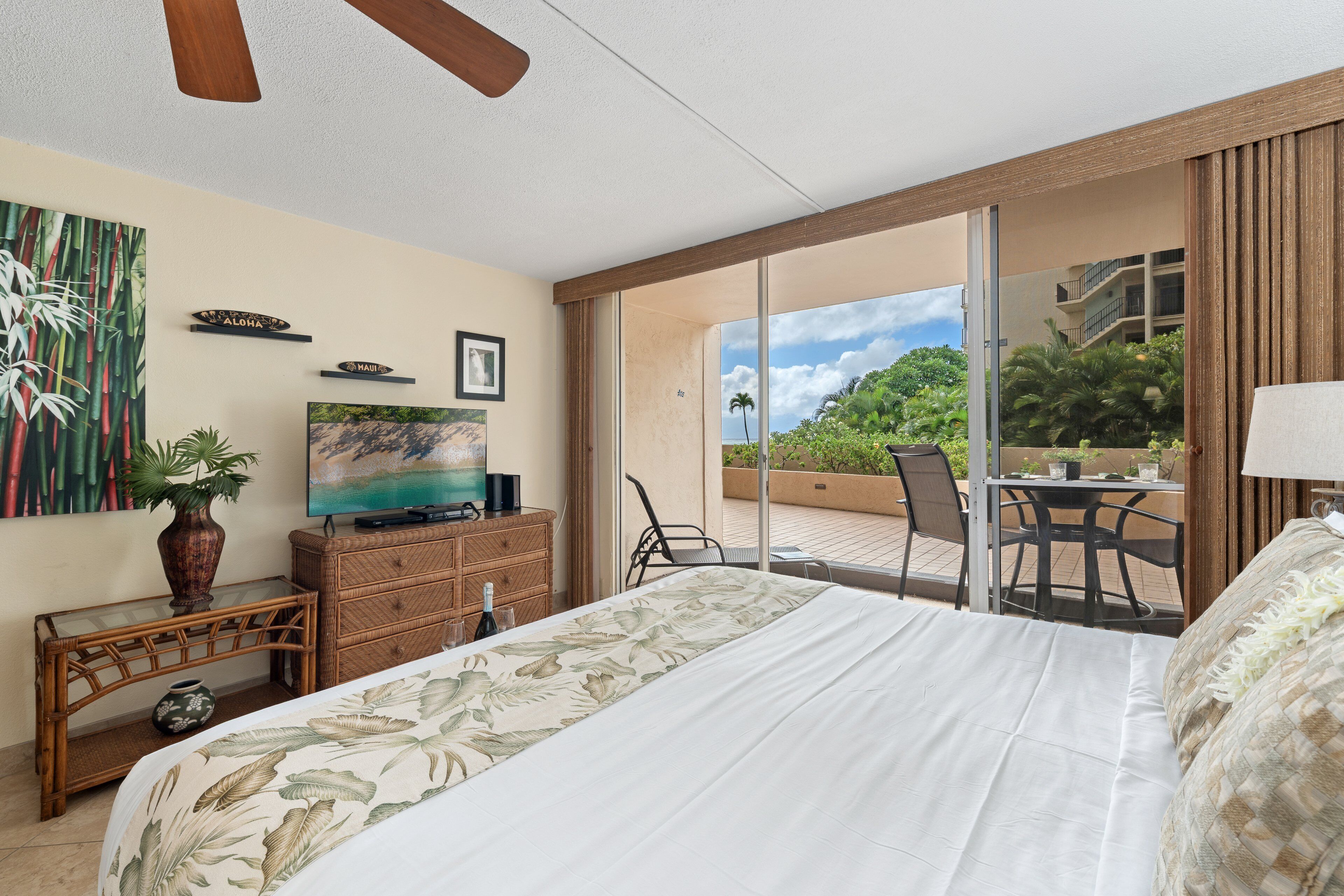 Une chambre d’hôtel comprenant un lit, une télévision, un coin repas avec des chaises et une vue sur la verdure environnante.