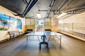 Una sala de conferencias con una mesa, sillas y un banco. Hay ventanas con vistas a palmeras y una playa.