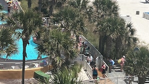 Ein Strandresort mit Swimmingpool, Palmen und freiem Blick auf den Ozean.