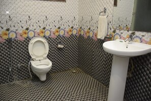 A bathroom with a toilet, sink, and decorative tiles.