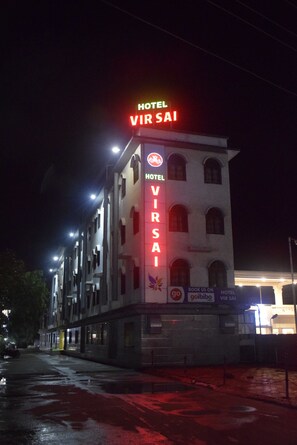 A hotel named 'Hotel VirSai' with a prominent neon sign, multiple floors, and a visible entrance.