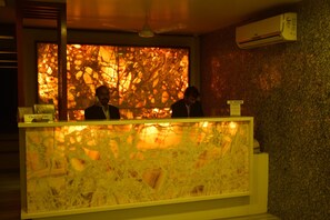 A reception desk with a check-in counter, a no smoking sign, and an air conditioning unit on the wall.