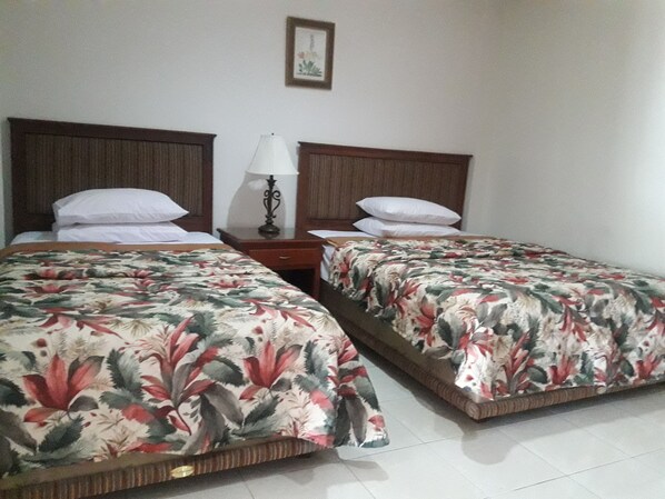 A hotel room with two single beds, a nightstand with a lamp, and a framed picture on the wall. - S & C Hotel Suites And Apartments (Malakal Island)