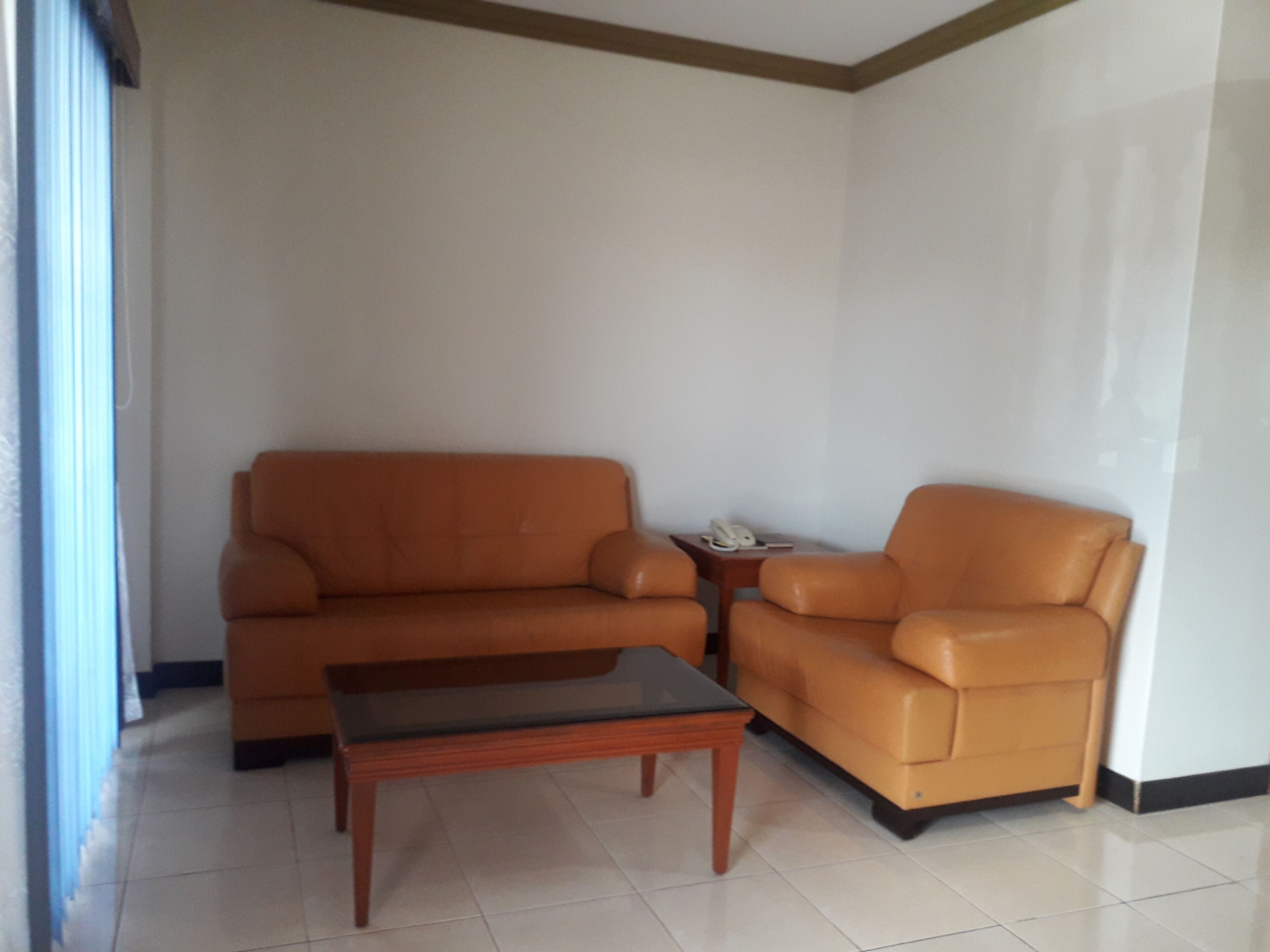 Una sala de estar con un sofá marrón, un sillón a juego y una pequeña mesa de centro de madera.