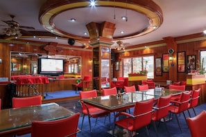 Relax in style with a spacious room featuring a dining area, TV, and bar, surrounded by artwork and large windows.