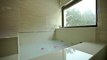 A bathroom with a bathtub, a window, and a mirror.
