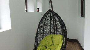 A hanging chair with a green cushion in a hallway with white walls and wooden flooring. - Sin Ging Hong Resort (Lugu)