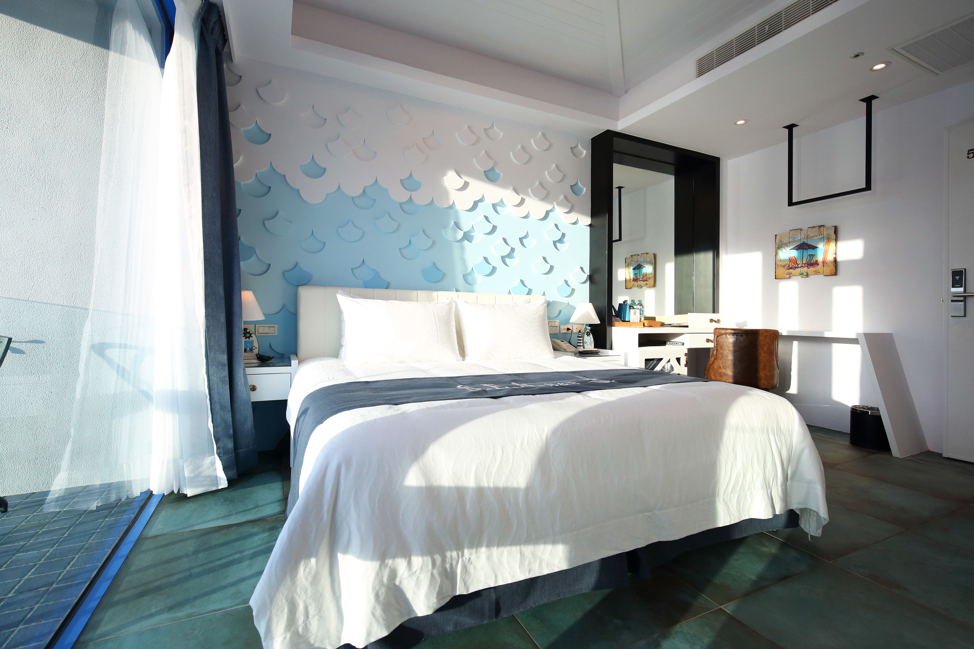 A modern hotel room with a large bed, a nightstand, a dresser, and a mirror.