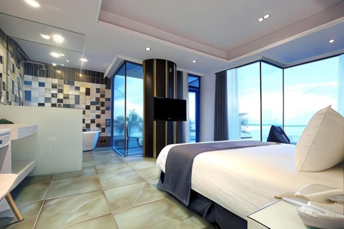 Una habitació d'hotel moderna amb un llit gran, televisió, bany i vista a la ciutat.