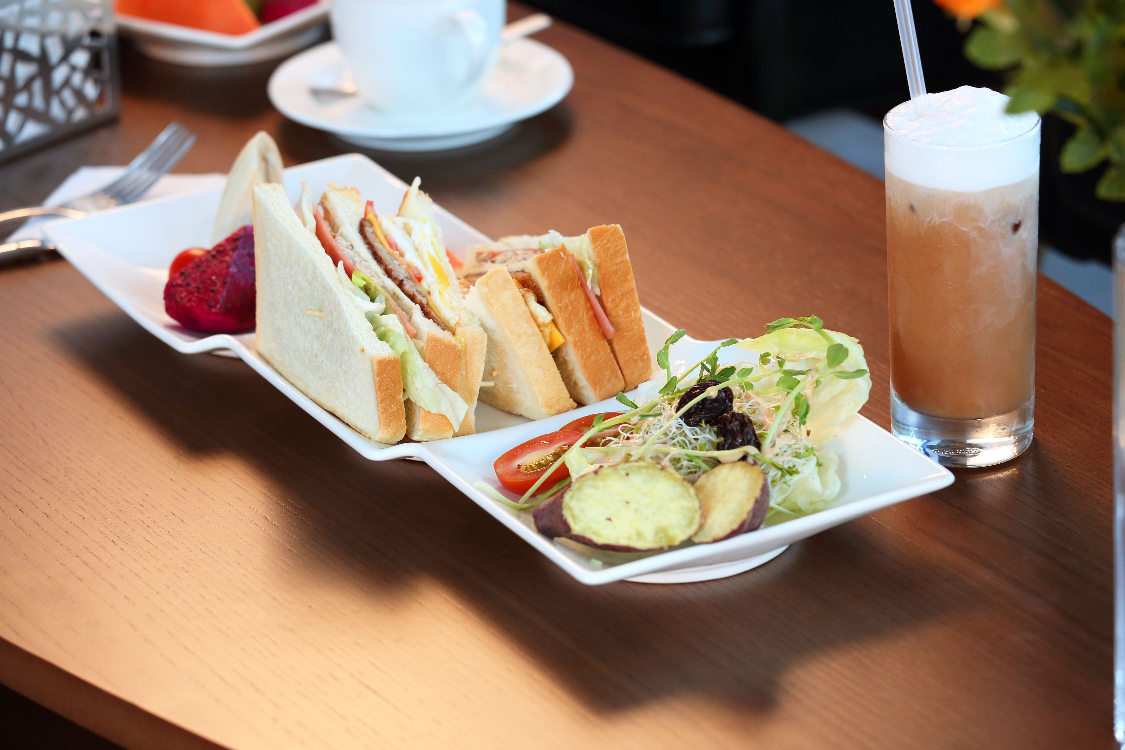 Una mesa con un sándwich, ensalada y bebida helada.