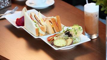 Una mesa con un sándwich, ensalada y bebida helada.