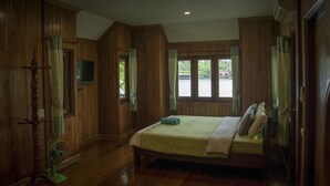 A wooden-paneled room with a bed, a fan, and a window with curtains. - Chantara Resort (Bang Khonthi)