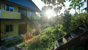A yellow building with a blue roof, surrounded by greenery and a wooden staircase. - Fanush Resort (Bandarban)