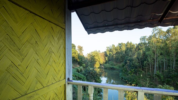 A wooden balcony with a view of a river and forest. - Fanush Resort (Bandarban)
