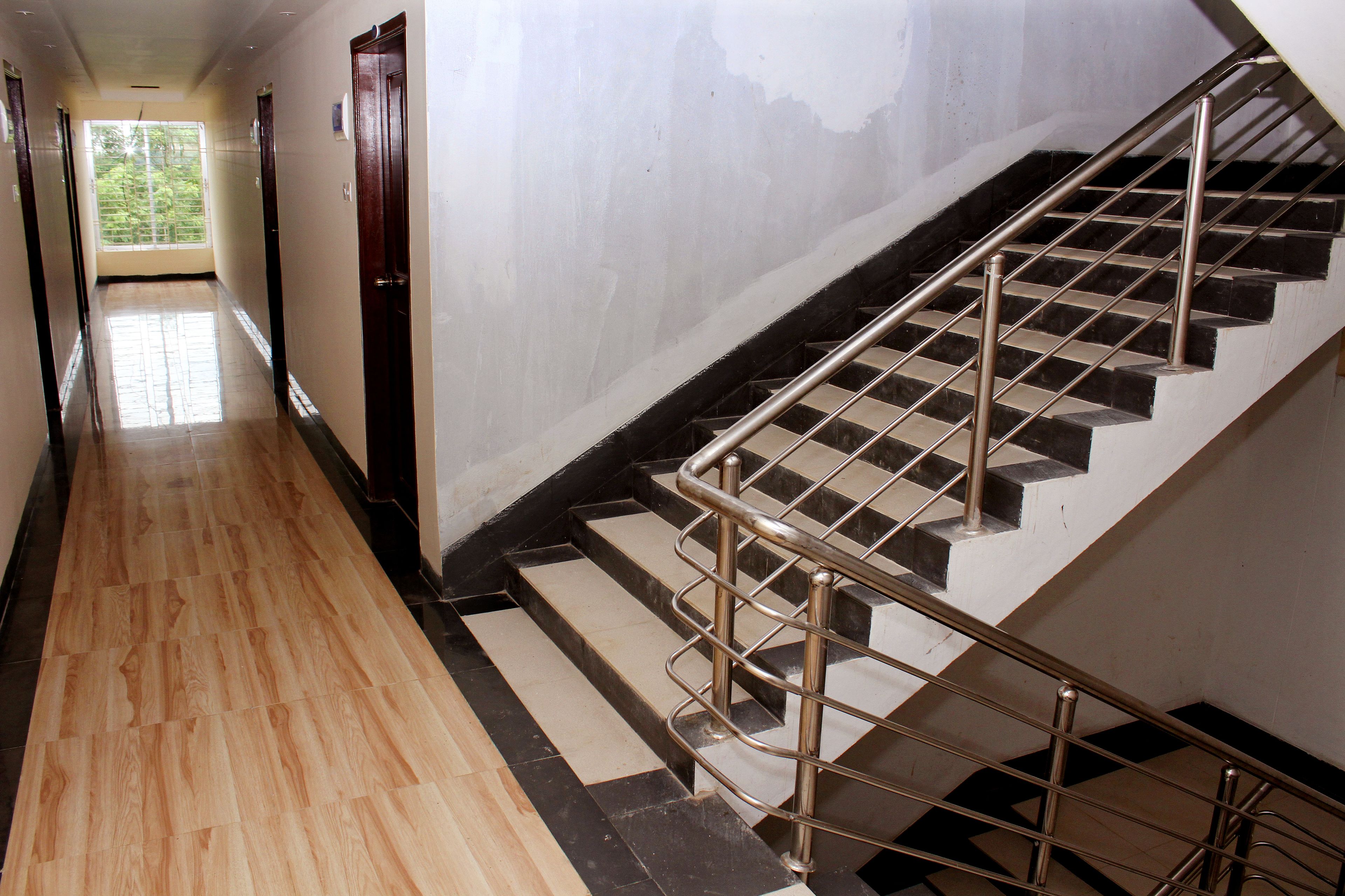 Un couloir doté d’un plancher en bois qui mène à un escalier avec des rampes en métal.