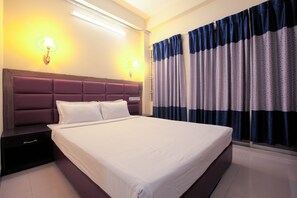 A neatly made bed with a headboard, a bedside table, and curtains on a window. - Hotel Night Heaven (Bandarban)
