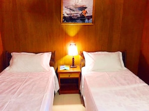 Una habitación con dos camas individuales, una mesita de noche con lámpara y un cuadro en la pared.