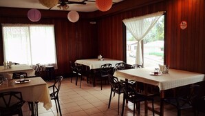 Un restaurant doté de nombreuses tables et chaises, de murs en bois et d’un sol carrelé.