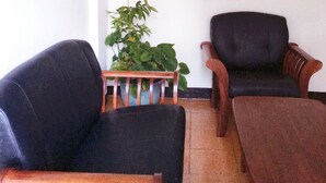 Une pièce avec deux fauteuils noirs, une table basse en bois et une plante en pot.
