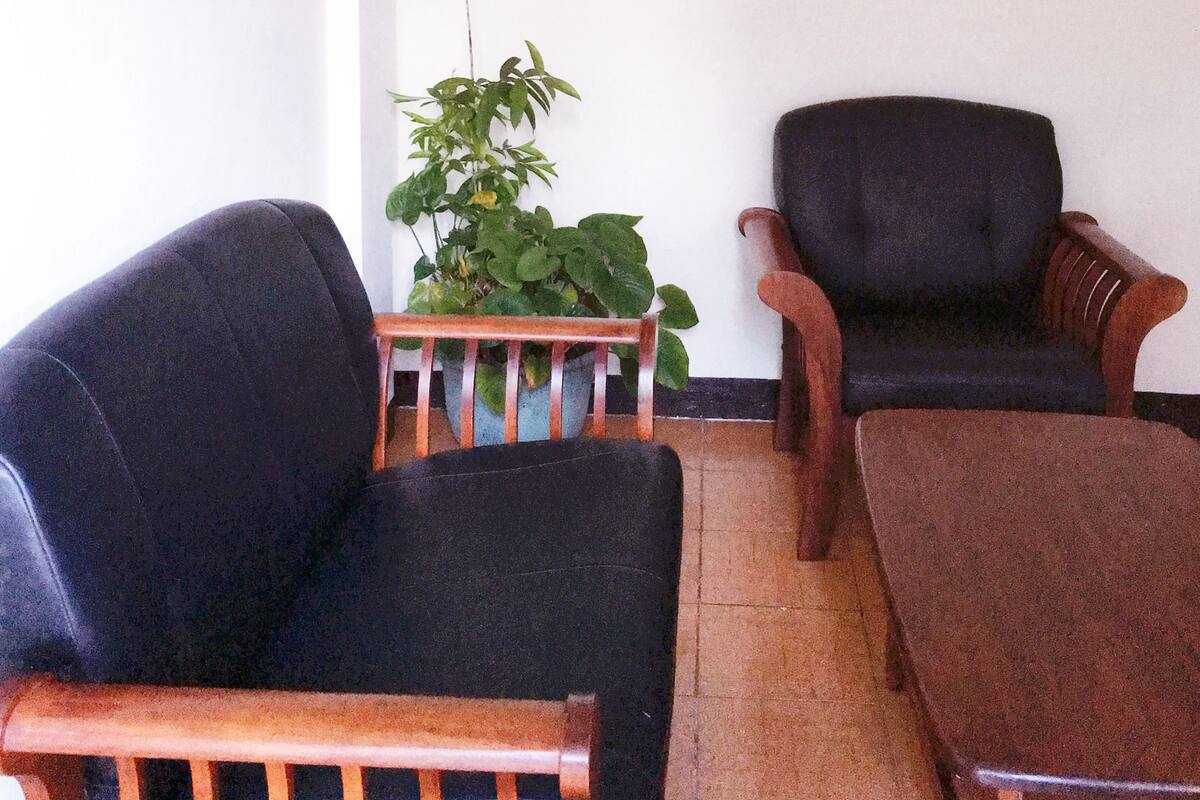 A room with two black armchairs, a wooden coffee table, and a potted plant.