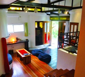 A cozy living area with a wooden floor, a red sofa, a small table, and a staircase leading to another level.