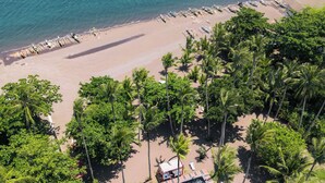 An aerial view of a beach with rows of sun loungers, palm trees, and a pool area. - SomeWhere Else Boutique Resort (Mambajao)