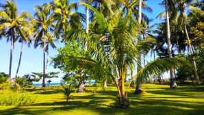A tropical landscape with palm trees and a view of the ocean. - SomeWhere Else Boutique Resort (Mambajao)