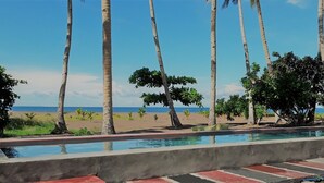 A swimming pool with a view of the beach and palm trees. - SomeWhere Else Boutique Resort (Mambajao)