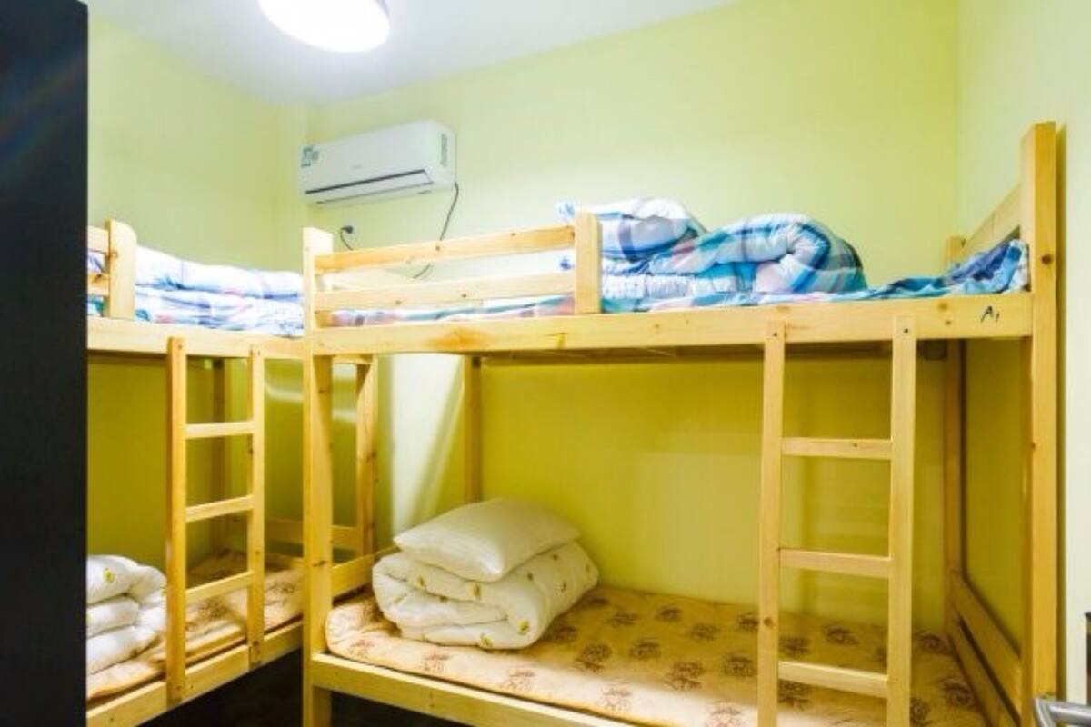 Habitación con literas de madera, una escalera y aire acondicionado instalado en la pared.