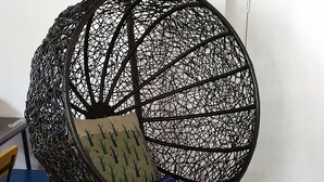 A spherical hanging chair with a cushion, a wooden floor, and a door in the background. - Suzhou Chope Hostel (Suzhou)