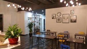 A modern cafe with tables and chairs, potted plants, and wall art. - Suzhou Chope Hostel (Suzhou)