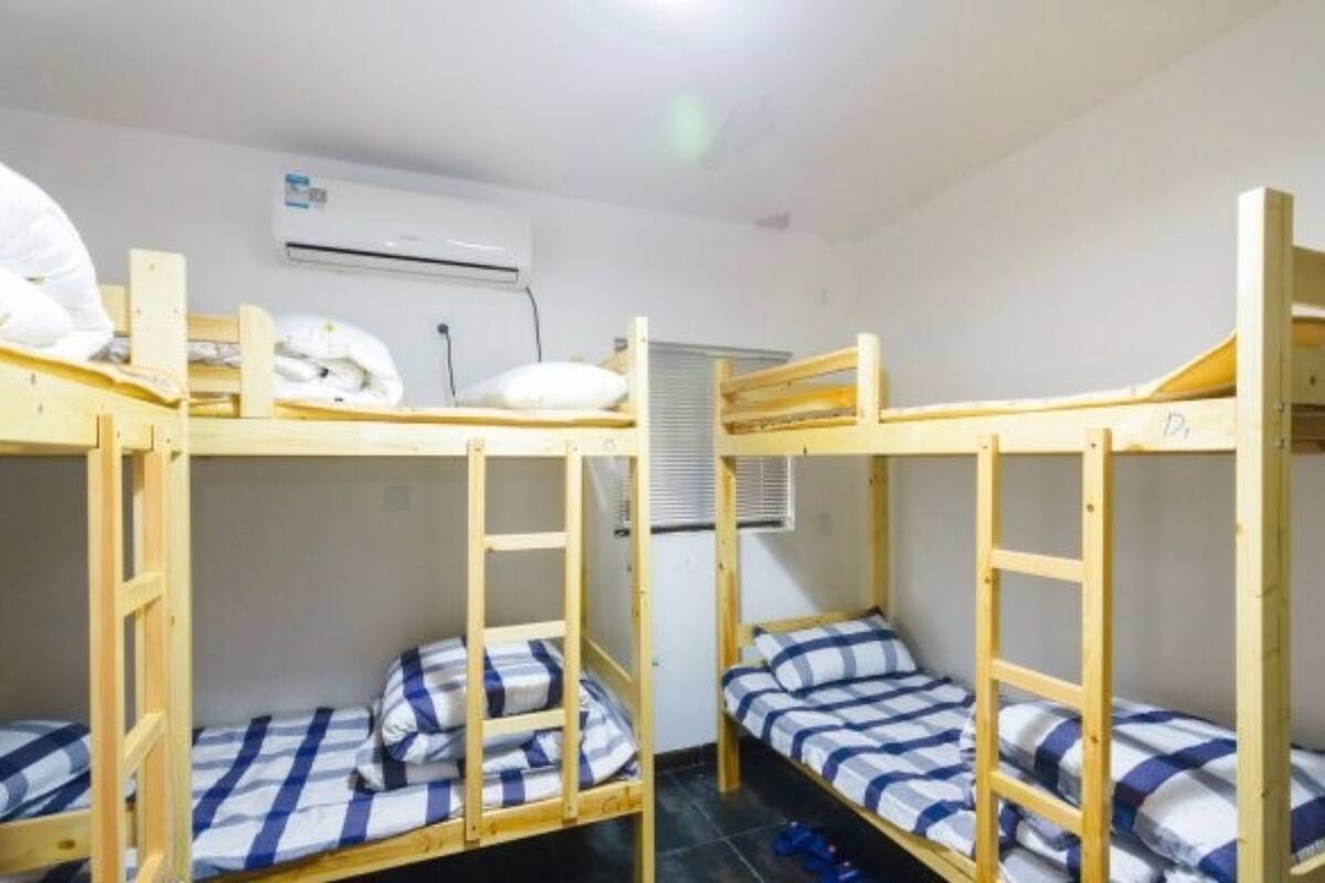 Un dormitorio con literas, un equipo de aire acondicionado y una ventana con persianas.