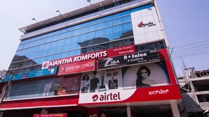A building with multiple advertisements, including 'Ajantha Komforts' and 'Chung Wah Express'. - Ajantha Komforts (Bengaluru)