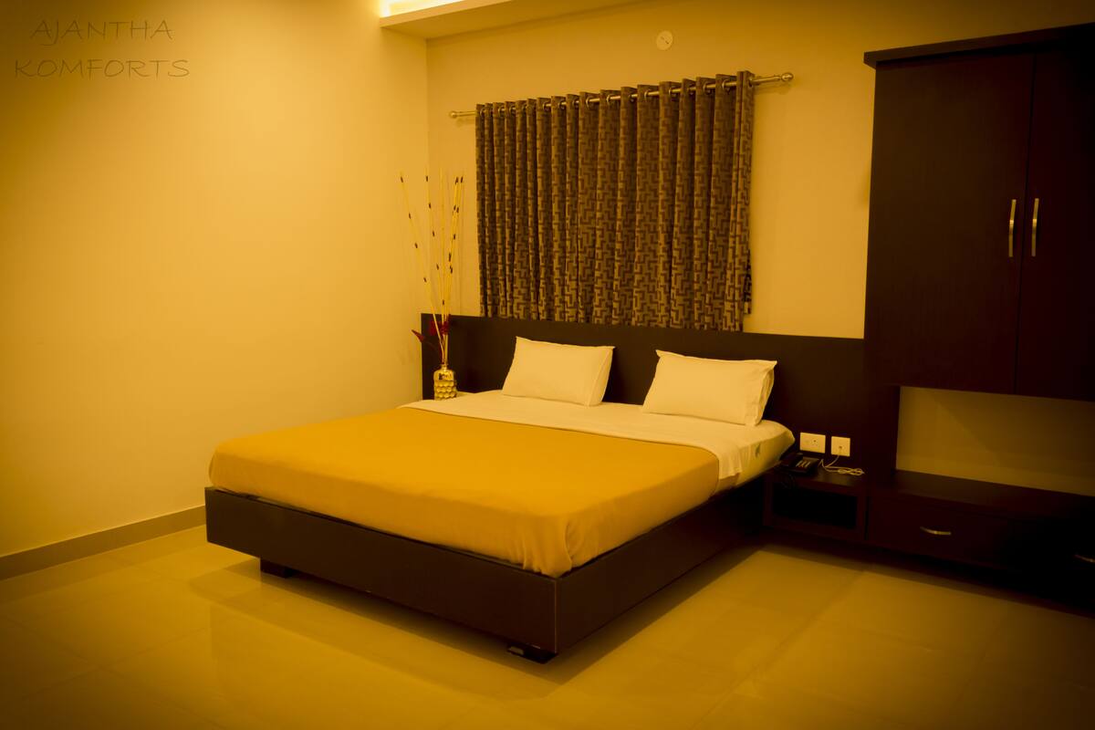 A bedroom with a large bed, a wardrobe, and a nightstand.