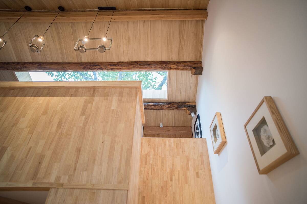 A wooden interior with exposed beams, a staircase, and framed pictures on the wall.