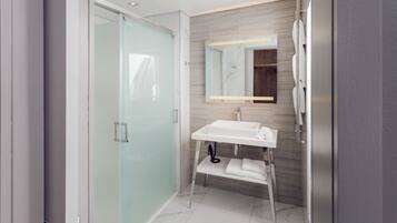 A modern bathroom with a glass shower enclosure, a white sink, and a wooden vanity.