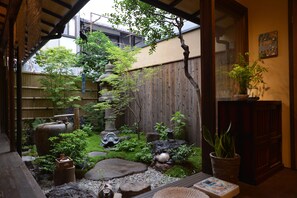 Un jardin japonais traditionnel, agrémenté d’une clôture en bois, de lanternes en pierre et de diverses plantes.