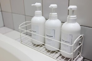 A bathroom shelf with three white bottles labeled shampoo, conditioner, and body wash. - Guesthouse Bokuyado - Hostel (Kyoto)
