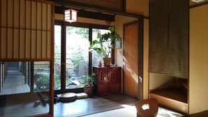 A traditional Japanese room with tatami flooring, a shoji screen, a wooden desk, and a potted plant. - Guesthouse Bokuyado - Hostel (Kyoto)
