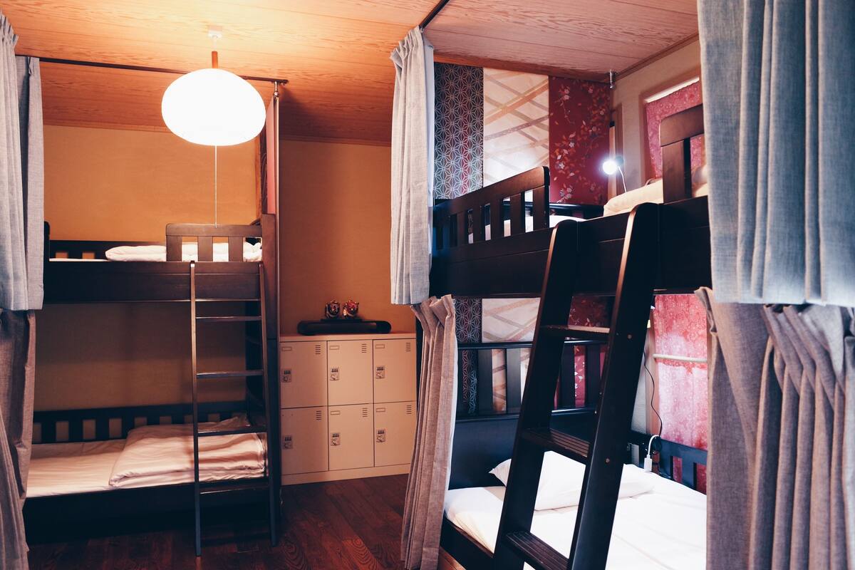 Habitación con literas, una escalera, un escritorio y un mueble pequeño.
